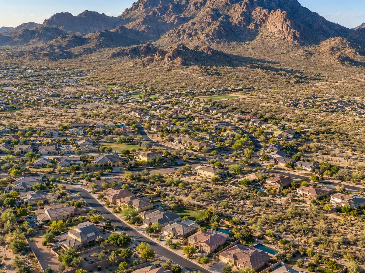 Aerial drone view of a new-build neighborhood in San Tan Valley, Arizona, with mountains rising behind it.