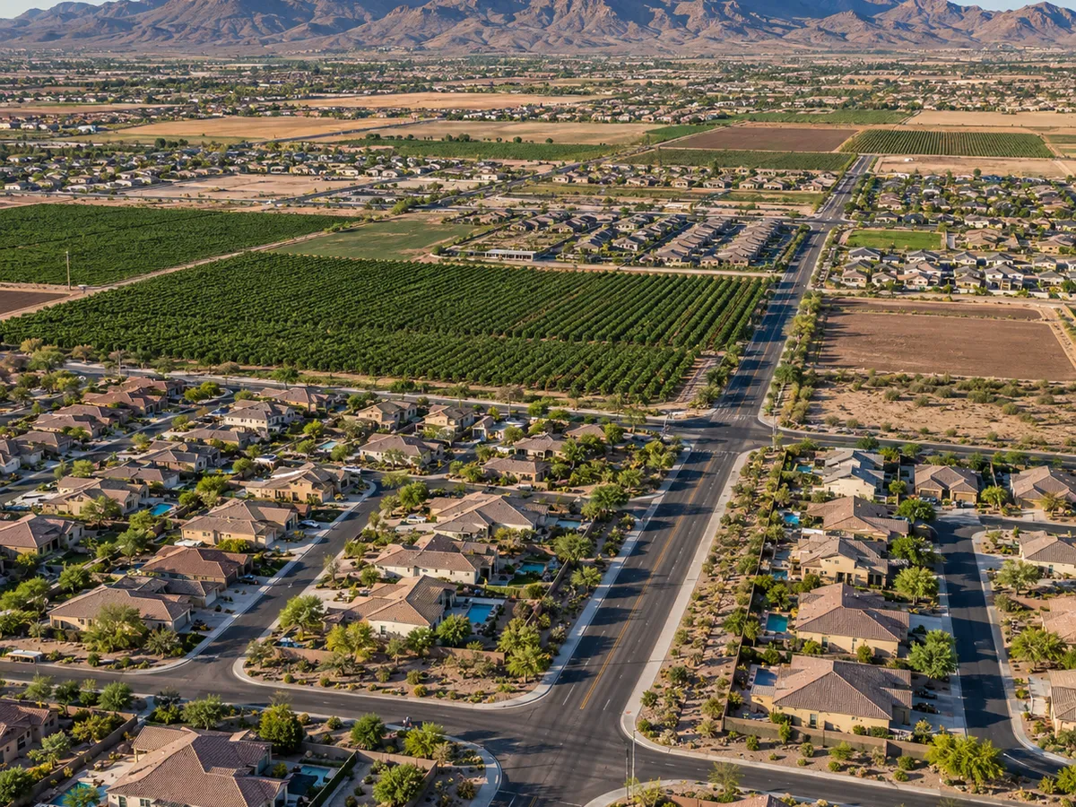 Aerial drone view of orchard fields bordering a suburban neighborhood in Queen Creek, Arizona.